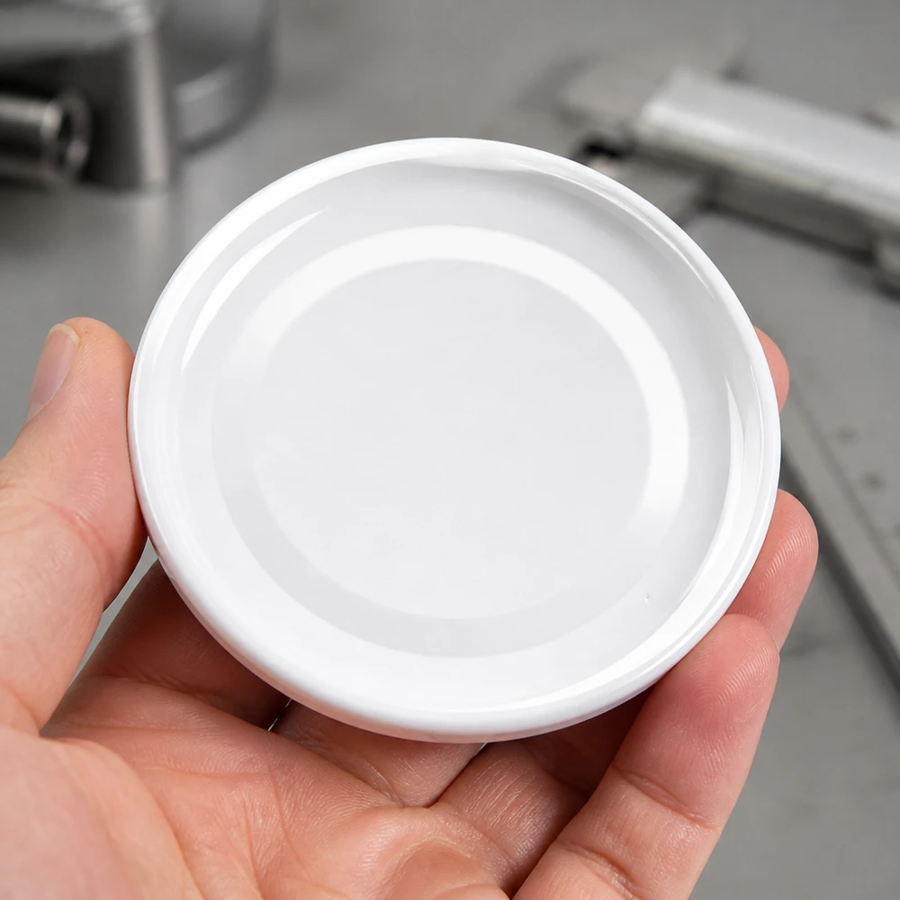 43mm BasicSeal Deckel weiss (TO43) UNiTWIST 43mm BasicSeal Twist-Off Deckel TO43 weiss aus Metall in der Hand eines Gewerbetreibenden Pacadura